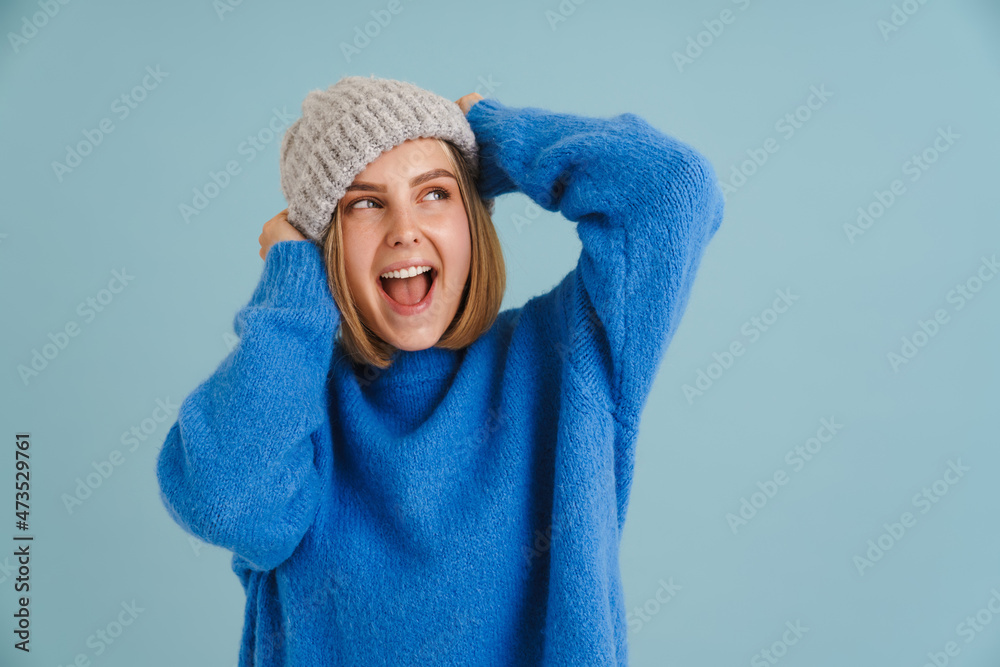 Young blonde woman wearing knit hat smiling and winking at camera