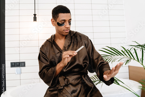 Black man with eye patches doing manicure with nail file