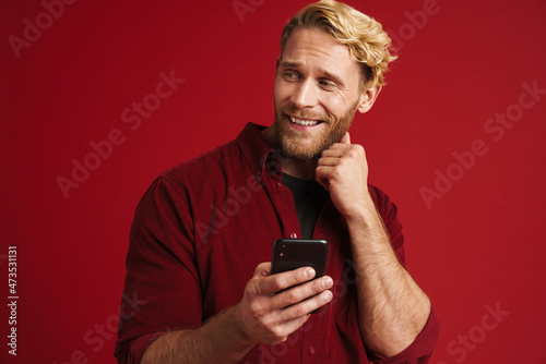 Bearded blonde man smiling and using mobile phone © Drobot Dean