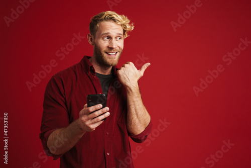 Bearded blonde man pointing finger aside and using mobile phone © Drobot Dean