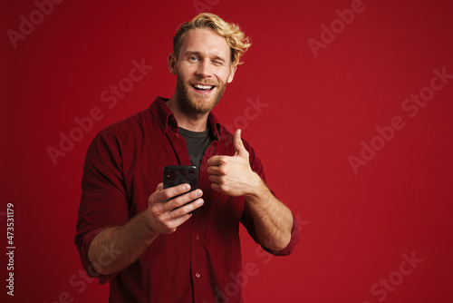 Bearded blonde man showing thumb up and using mobile phone © Drobot Dean