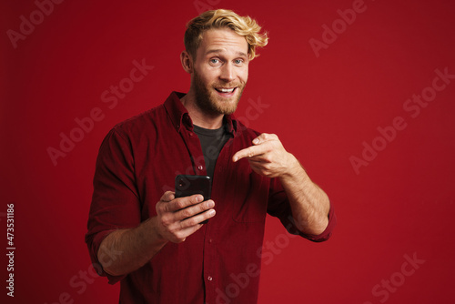 Bearded blonde man pointing finger at his mobile phone © Drobot Dean