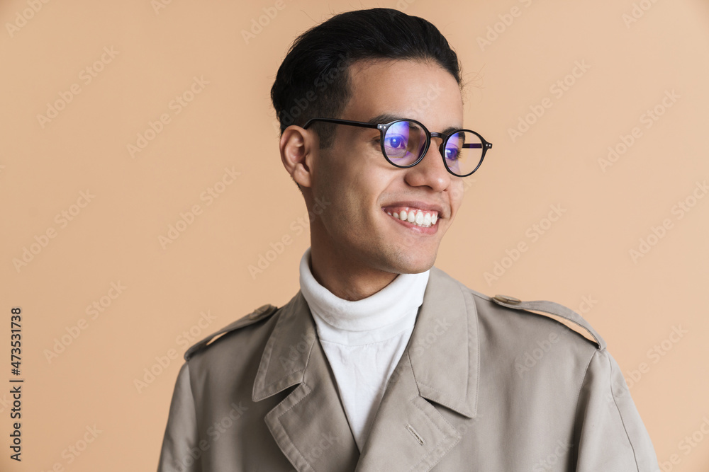 Young middle eastern man in eyeglasses smiling and looking aside