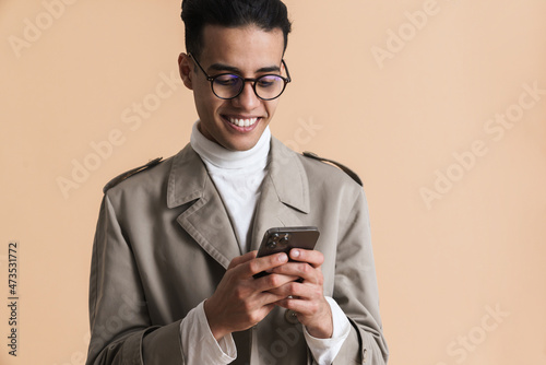 Young middle eastern man in eyeglasses using mobile phone