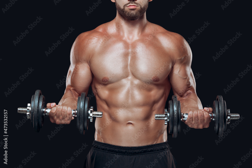 Close up of muscular body and strong hands lifting heavy dumbbells isolated over black background