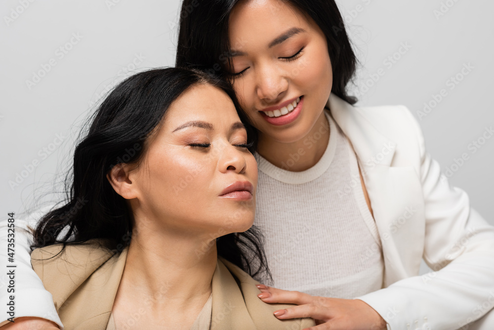 happy asian young daughter hugging mother isolated on grey happy asian young daughter hugging mother isolated on grey