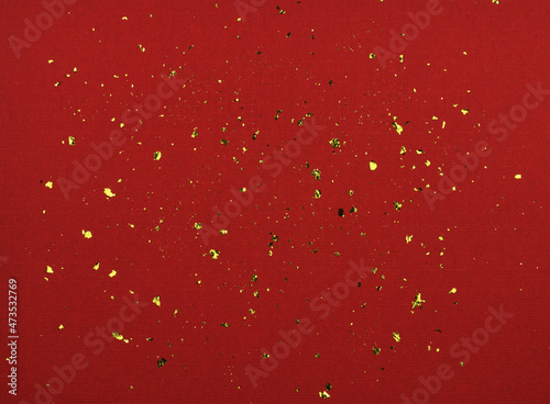 Golden flakes of potal on red textured paper photo