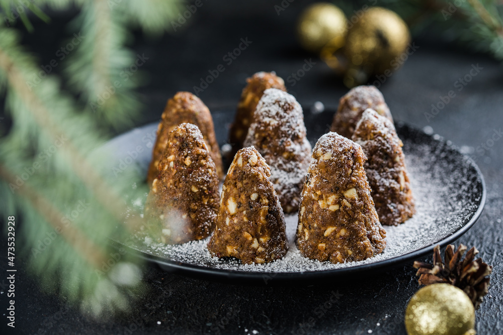 Delicious no bake chocolate Christmas dessert healthy energy pine cone, sprinkled with powdered sugar. Decorated with fir branches. Healthy Vegan dessert Delicious no bake chocolate Christmas dessert healthy energy pine cone, sprinkled with powdered sugar. Decorated with fir branches. Healthy Vegan dessert