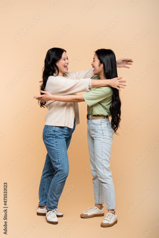 full length of asian with outstretched hands near happy adult daughter on beige full length of asian with outstretched hands near happy adult daughter on beige