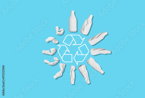 Recycling of plastic waste. A white plastic bottle is deformed against an empty blue background. Ecology, recycling, environmental protection, concept.