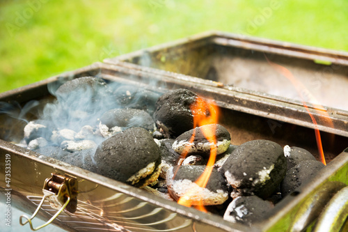 Burning coal briquets on grill in garden photo