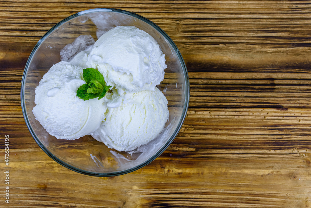 Glass bowl with ice cream balls and mint leaf on a wooden table. Top view Glass bowl with ice cream balls and mint leaf on a wooden table. Top view