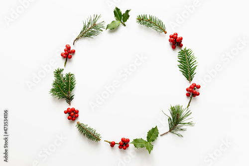 Christmas round frame made from holly berries and green twigs.