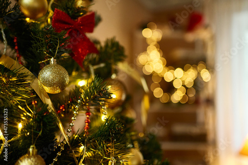 Close up decorated Christmas tree with golden balls, xmas toys, lights, glowing lamps in living room. Bokeh garlands on background photo