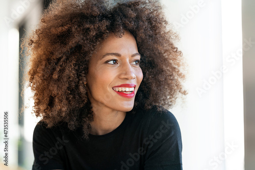Smiling businesswoman with frizzy hair looking away in office