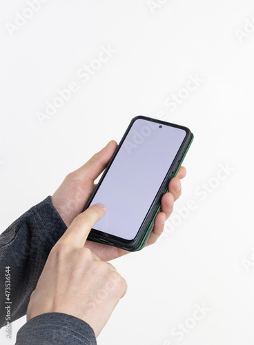 Fototapeta Naklejka Na Ścianę i Meble -  A smartphone in a case in the hands of a man, isolated on a white background with a blank screen (clipping contour) for the layout and template of a digital mobile smartphone. Selective focus