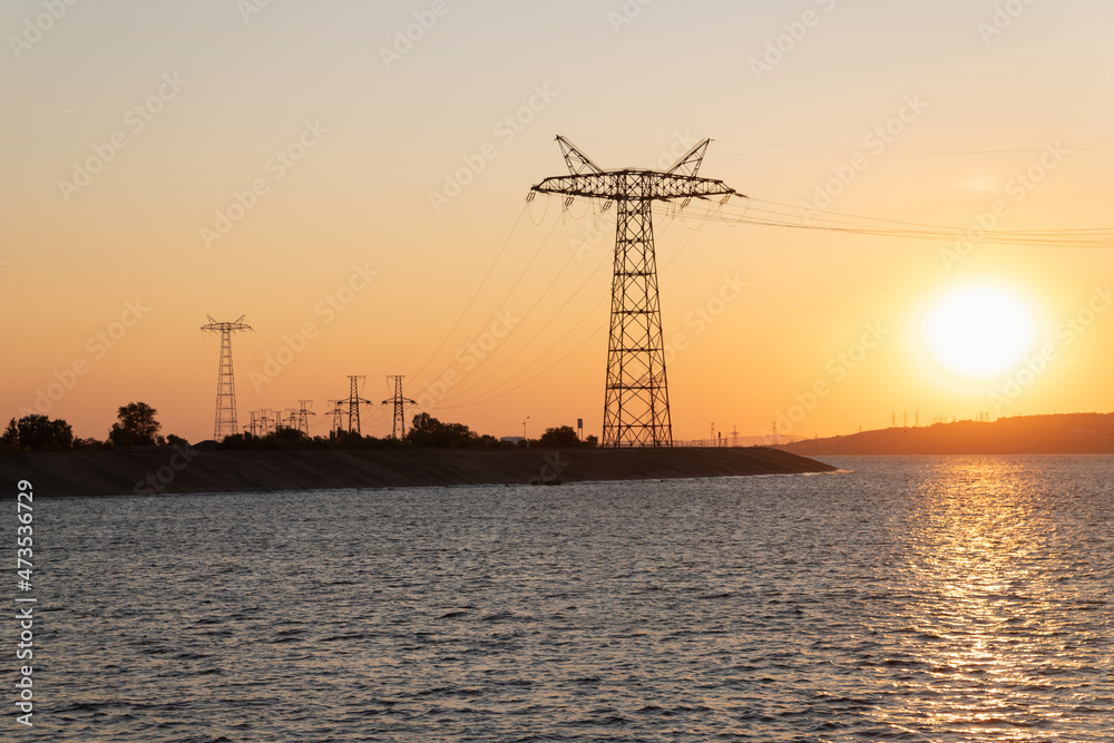 Power line on the river bank at sunset