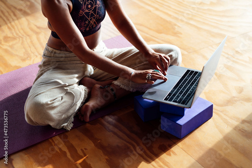 Woman using laptop while sitting on floor in gym photo