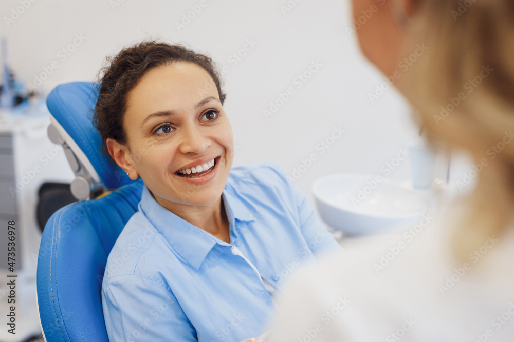 Woman in dental chair having conversation with doctor Woman in dental chair having conversation with doctor