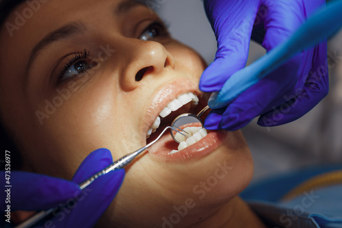 Dentist in gloves checking woman teeth