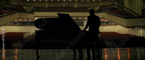Young aspiring musician entering stage of a huge concert hall as lights changing from ambient to stage. Shot with 2x anamorphic lens