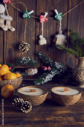 Two candles in a coconut shell on the background of the Christmas decor.