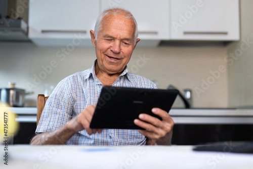 Senior man with tablet making purchases at home