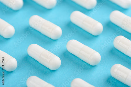 White transparent capsule pill pattern on blue background