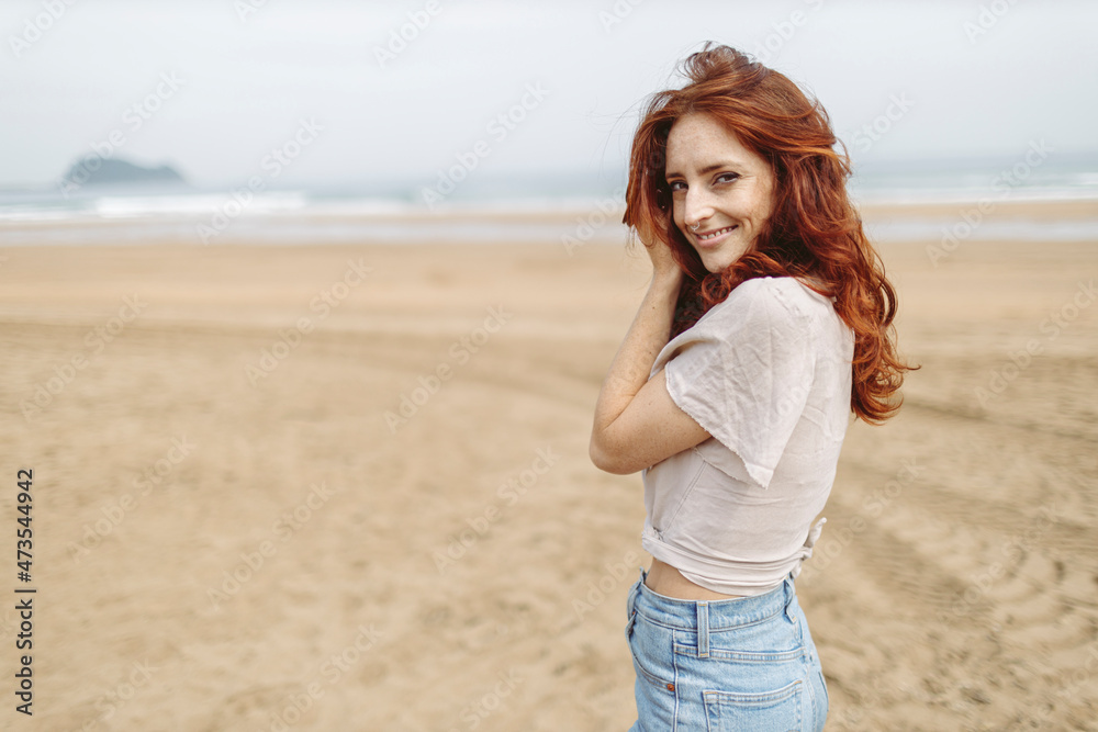 Smiling redhead woman standing at beach Smiling redhead woman standing at beach