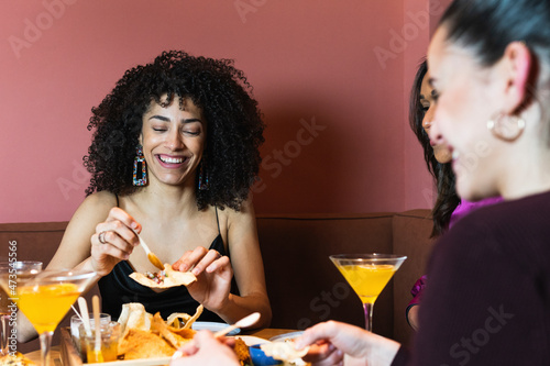 Smiling woman having appetizer with friends in restaurant
