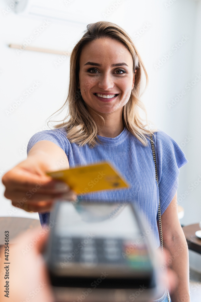 Smiling young woman making payment through credit card at coffee shop Smiling young woman making payment through credit card at coffee shop