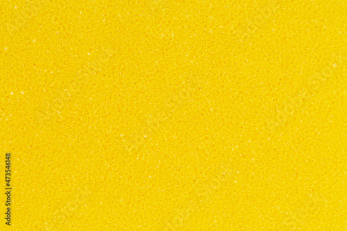 Bright yellow color foam sponge porous texture background. Extreme close-up view of detail abstract synthetic material. Horizontal composition