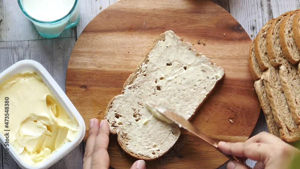 spreading butter on a bread on a chopping board