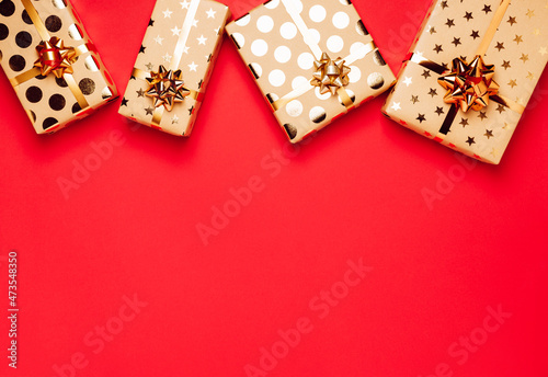 Gift boxes with golden bows and ribbons on red background. Copy space for your text. Top view photo