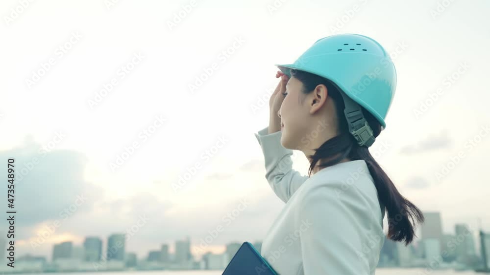 ヘルメットをかぶって都市を眺める女性　設計士　建築家