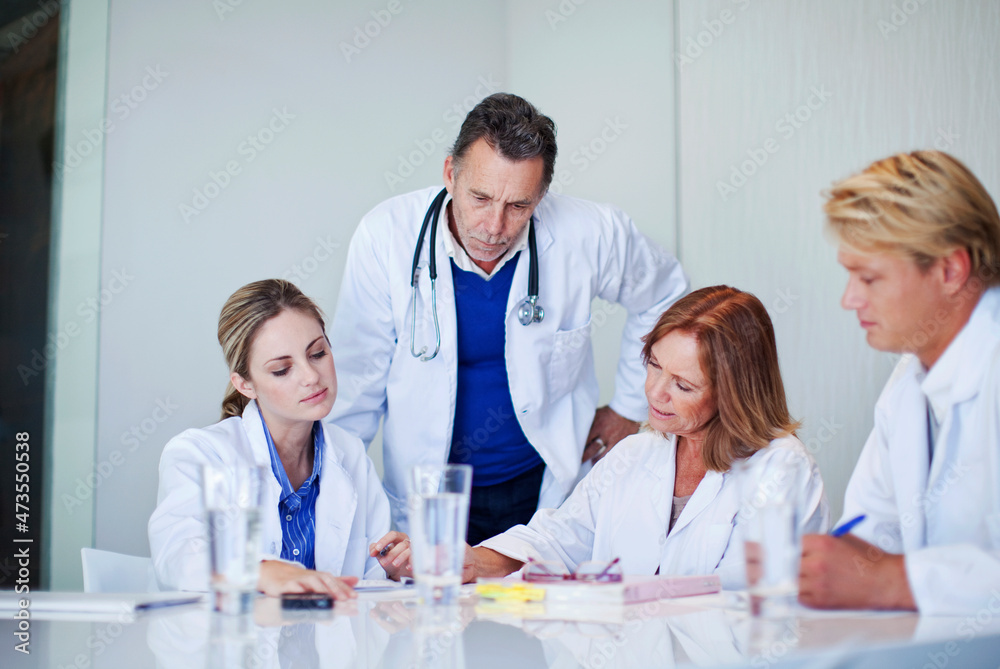 Mature female doctor assessing healthcare workers in meeting at hospital Mature female doctor assessing healthcare workers in meeting at hospital