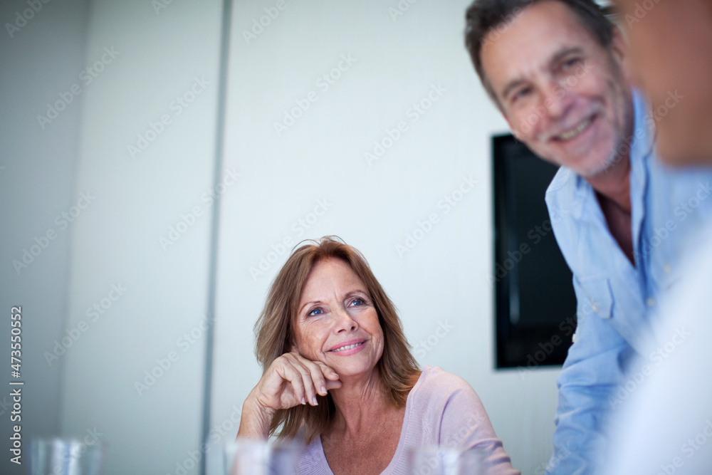 Smiling businesswoman looking away while male colleagues discussing in office Smiling businesswoman looking away while male colleagues discussing in office