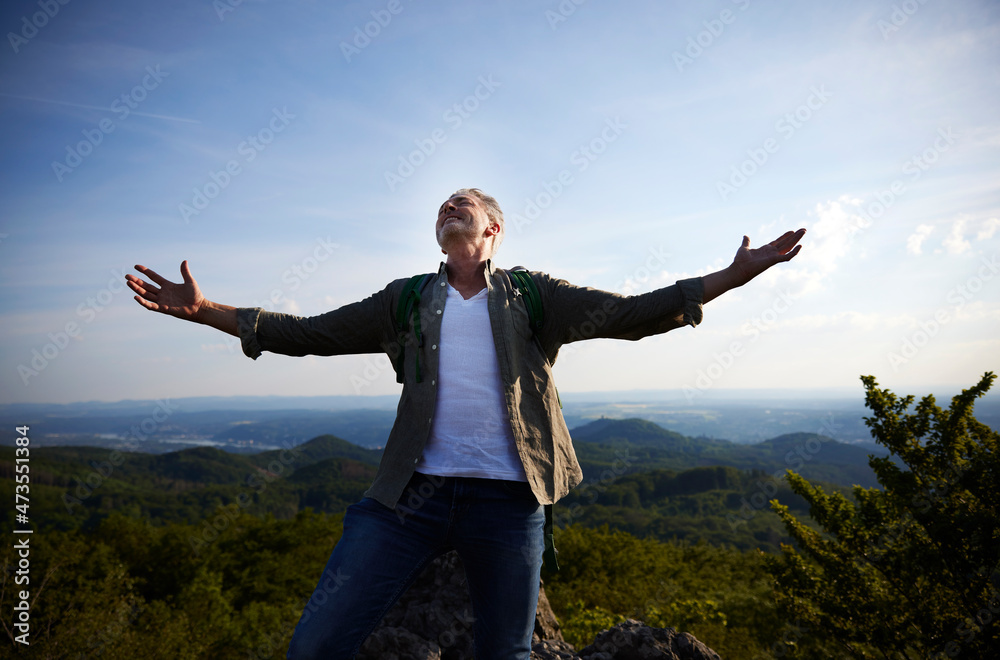 Carefree man standing with arms outstretched on mountain Carefree man standing with arms outstretched on mountain