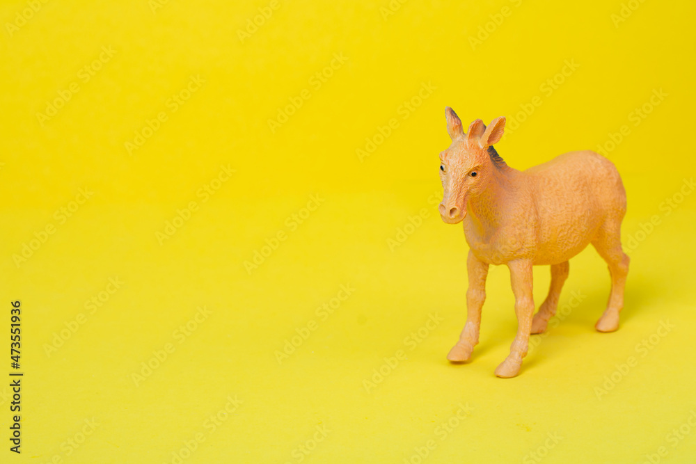 Baby toy horse made of plastic on a yellow background with copy space. Cute children toy brown horse on colored background. Baby toys concept