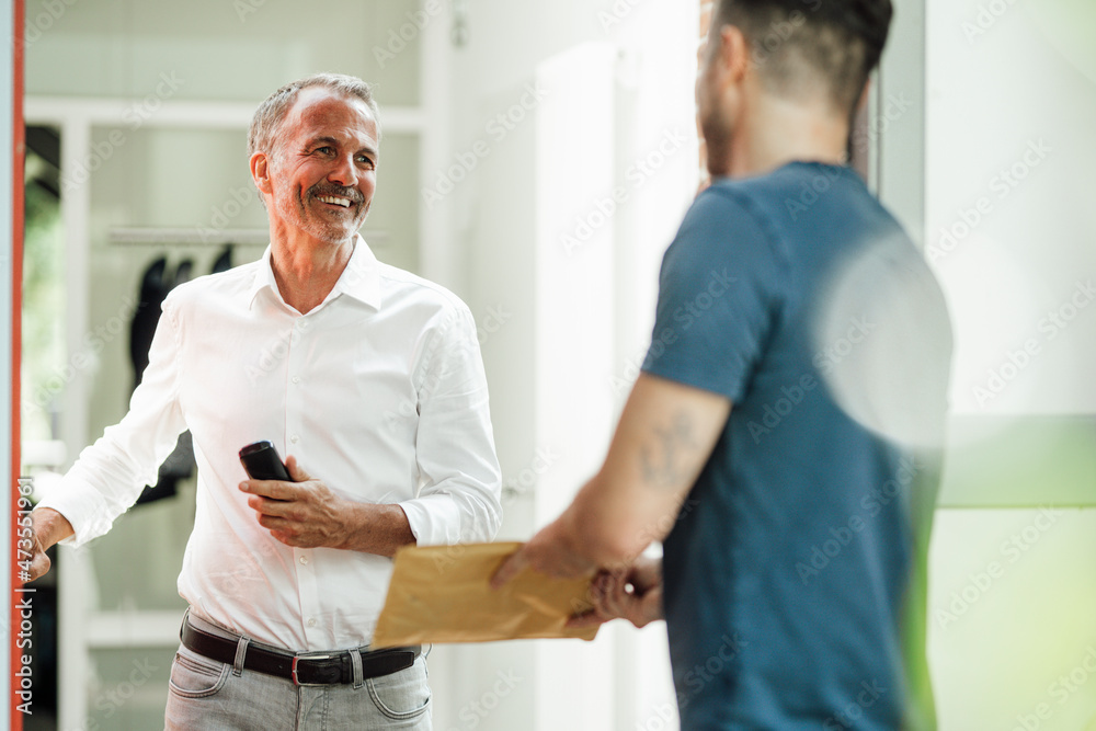 Smiling man looking at delivery person at doorway Smiling man looking at delivery person at doorway