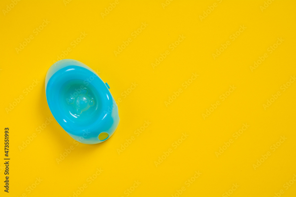 Blue baby potty on a yellow background with copy space. Children plastic toilet on colored background. Baby toys concept