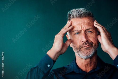 Thoughtful businessman with head in hands against green background photo