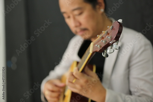 Portrait of men musician playing guitar in studio.