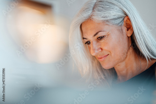 Mature businesswoman with white hair looking down at office