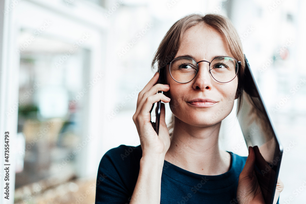 Female freelancer looking away while talking on smart phone and digital tablet Female freelancer looking away while talking on smart phone and digital tablet