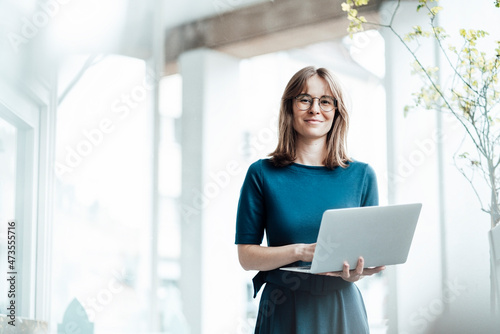 Wallpaper Mural Female business professional holding laptop while standing in cafe Torontodigital.ca