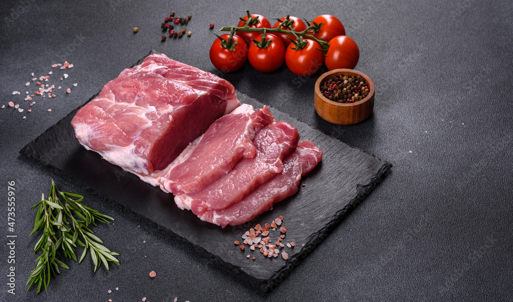 Raw pork steak on a cutting board with herbs and spices