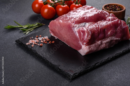 Raw pork steak on a cutting board with herbs and spices