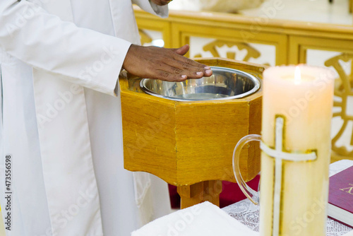 Slika na platnu Pastor at the christening ceremony with the hand over baptismal font