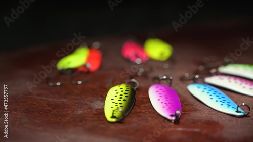 Spinners of different colors and shapes for fishing on a brown table. Background in blur.